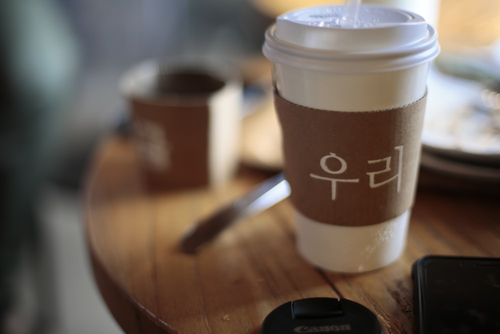 white and brown coffee cup on brown wooden table