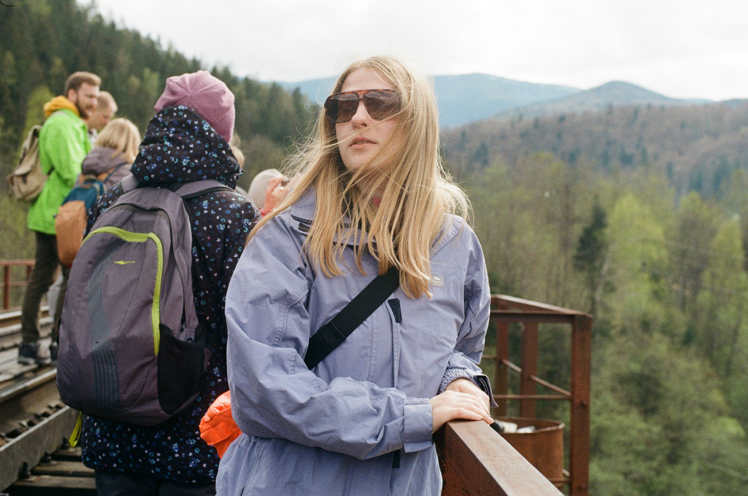 woman in gray jacket sitting on brown wooden bench during daytime