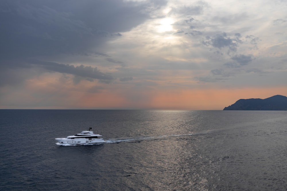 white boat on sea during sunset