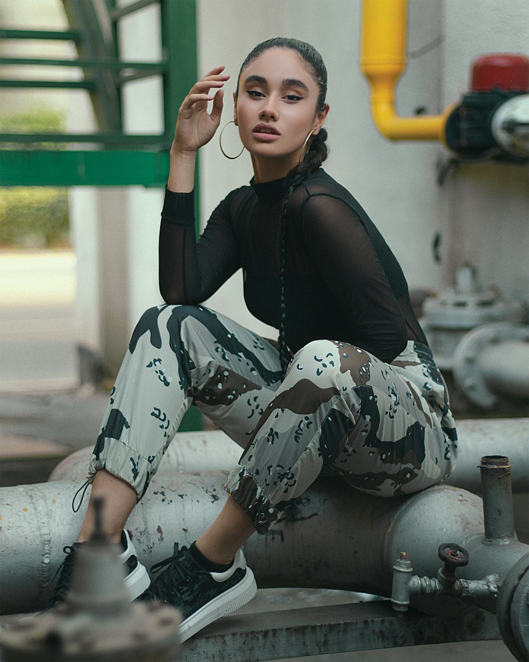 woman in black jacket and white pants sitting on green metal bar