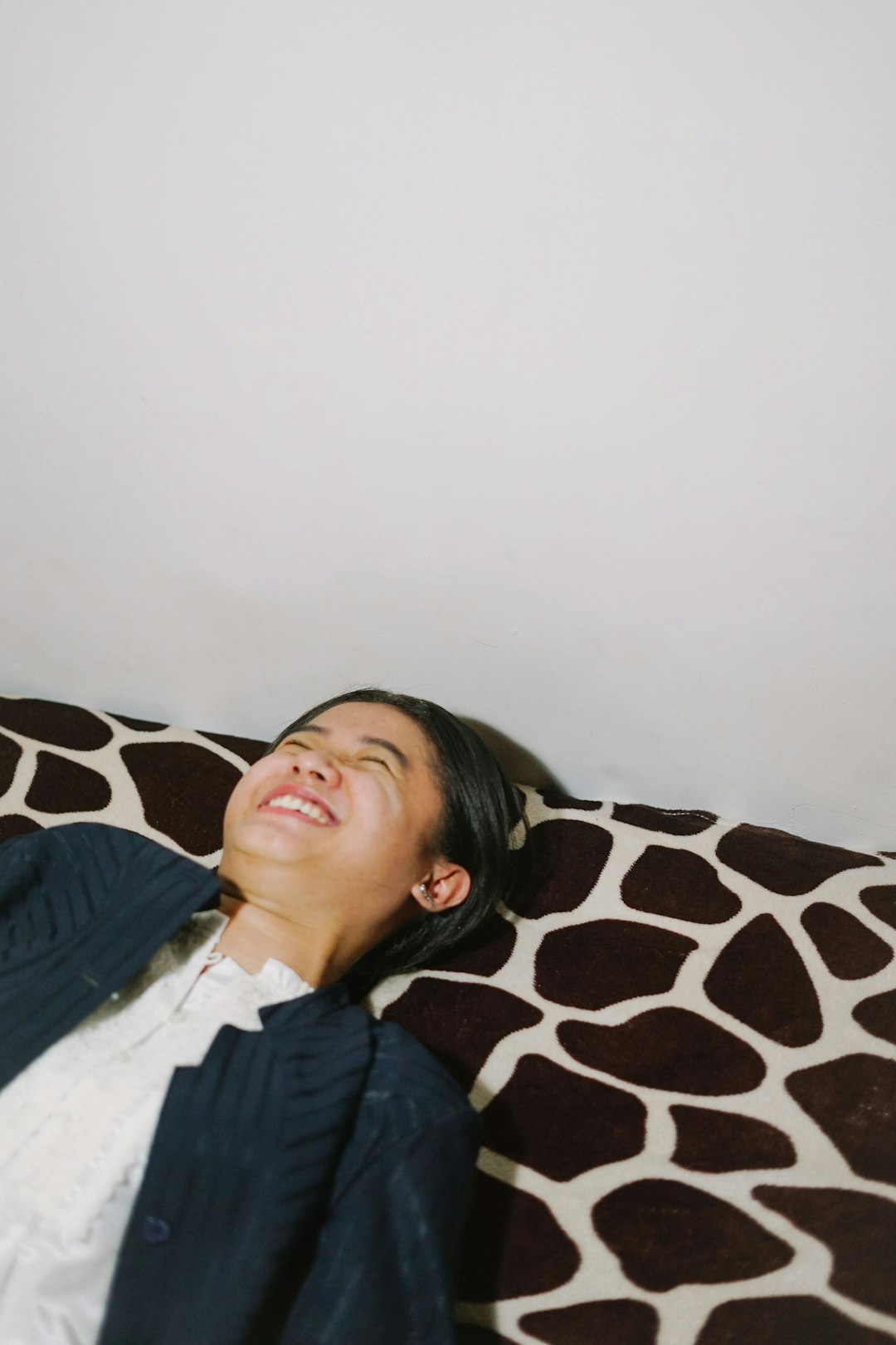 woman in black jacket lying on black and white floral pillow