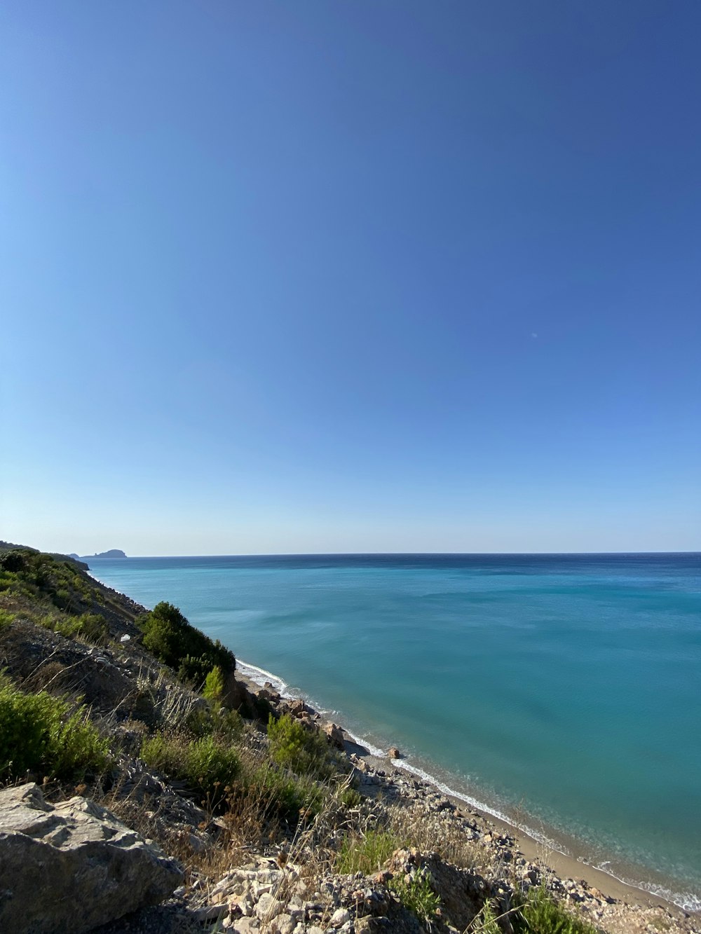 green grass field near sea under blue sky during daytime