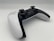 A modern video game controller with a sleek design featuring a combination of black and white colors. Two analog sticks, a directional pad, and various buttons are visible, positioned on a clean, minimalistic surface. The controller is angled slightly, giving a dynamic perspective.