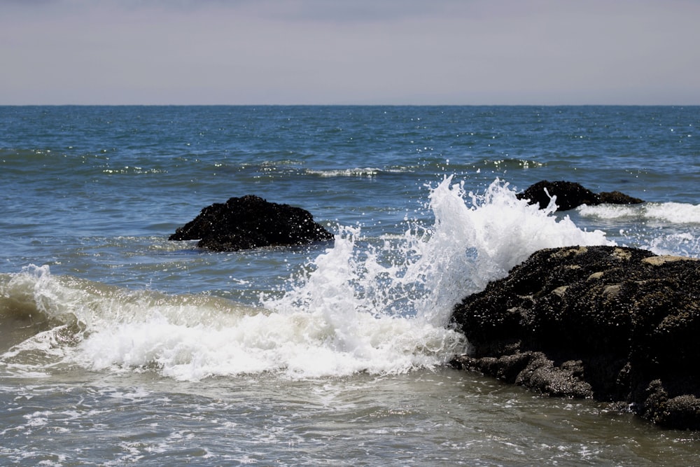 ocean waves crashing on black rock formation during daytime