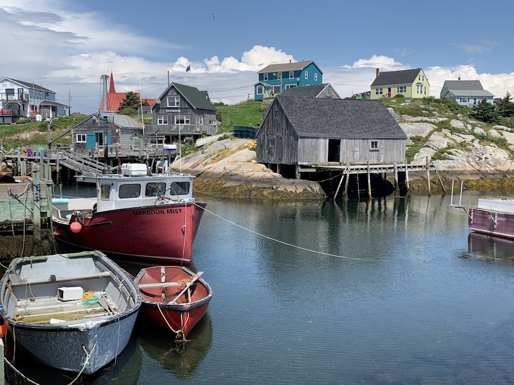 red and white boat on water near brown wooden house during daytime