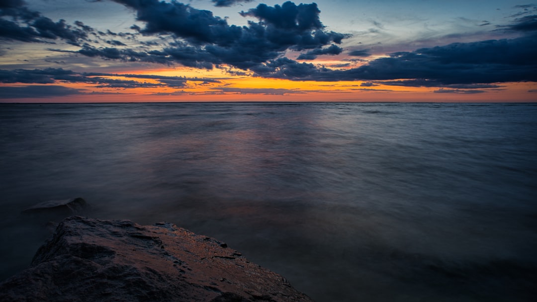 body of water under cloudy sky during sunset