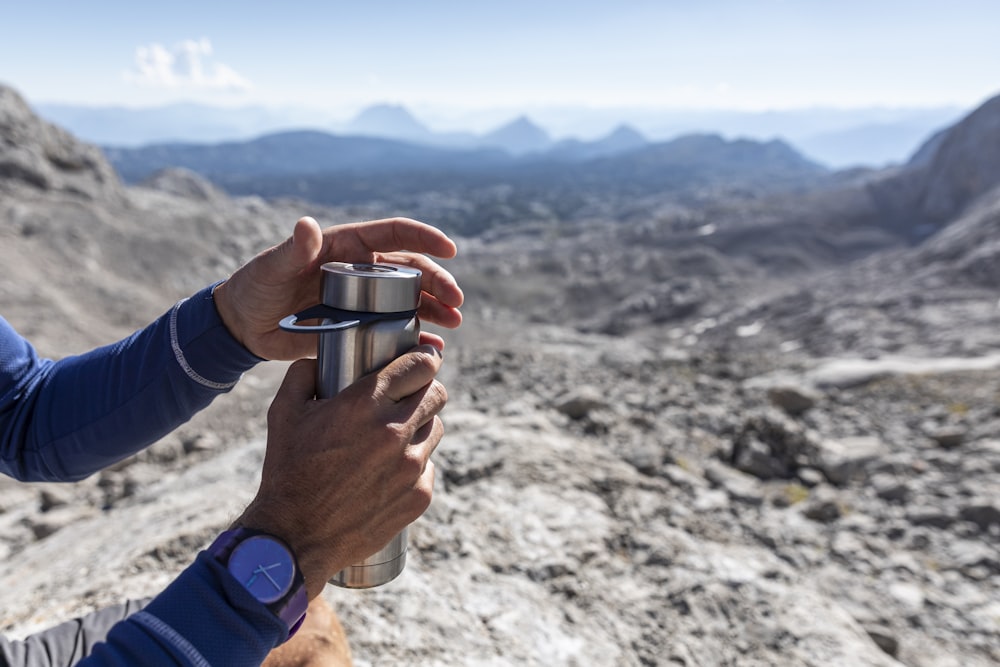 personne tenant une tasse en acier inoxydable