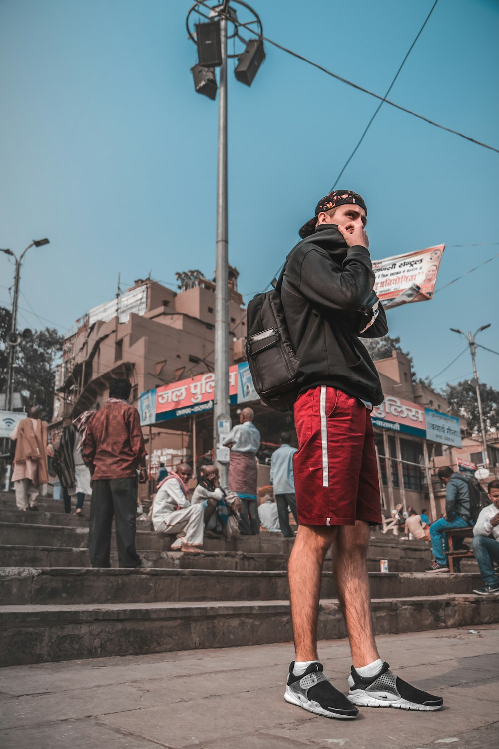 man in black jacket and red shorts standing on brown concrete stairs