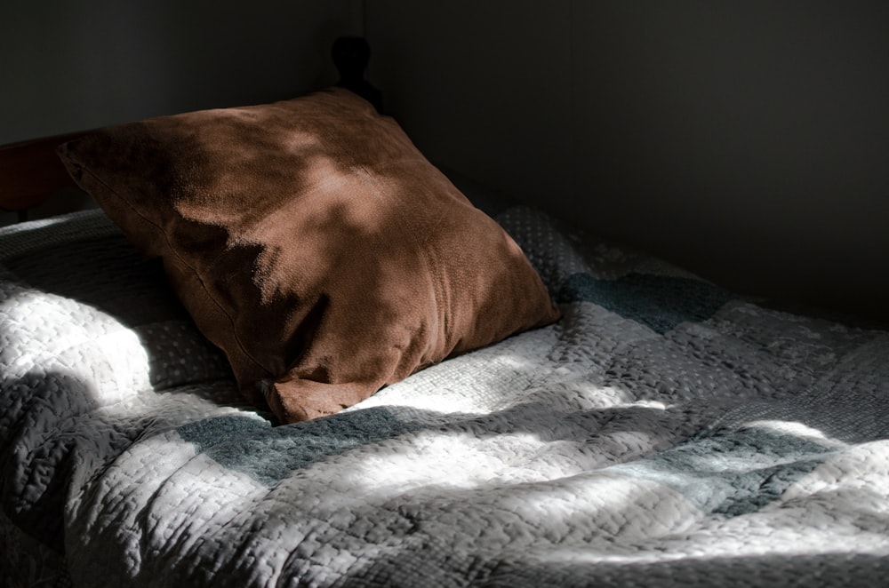 brown throw pillow on white and blue bed linen