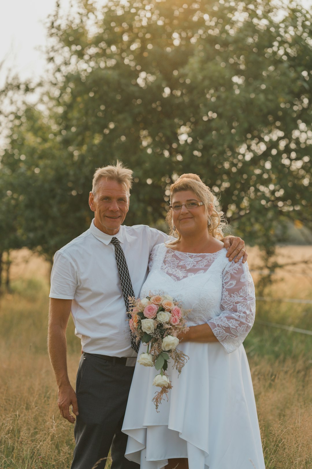 man in white dress shirt holding woman in white floral lace dress