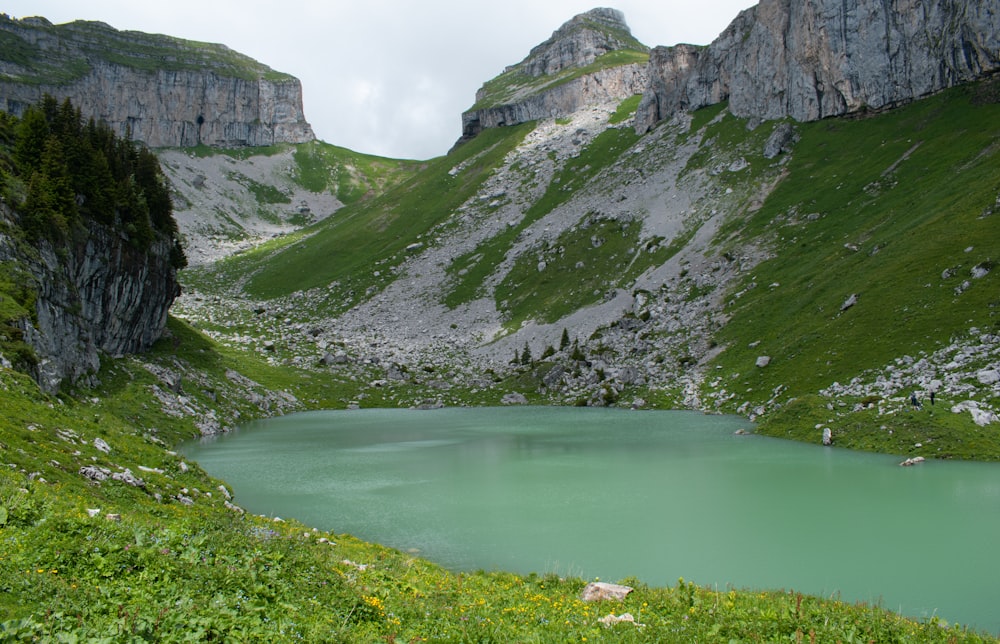 green lake between gray rocky mountains during daytime