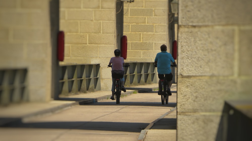 2 men riding bicycle on road during daytime