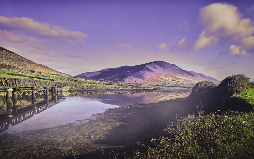 body of water near mountain during daytime