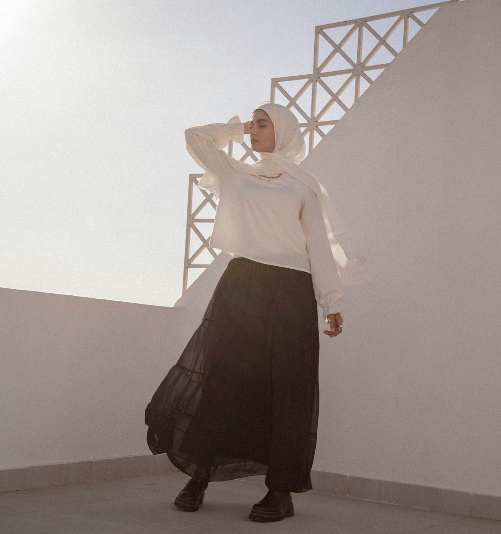 woman in white long sleeve shirt and black skirt standing on brown wooden floor