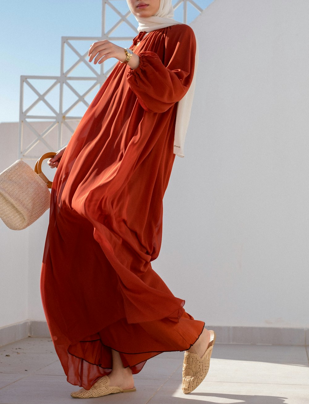 woman in orange dress sitting on white wicker chair