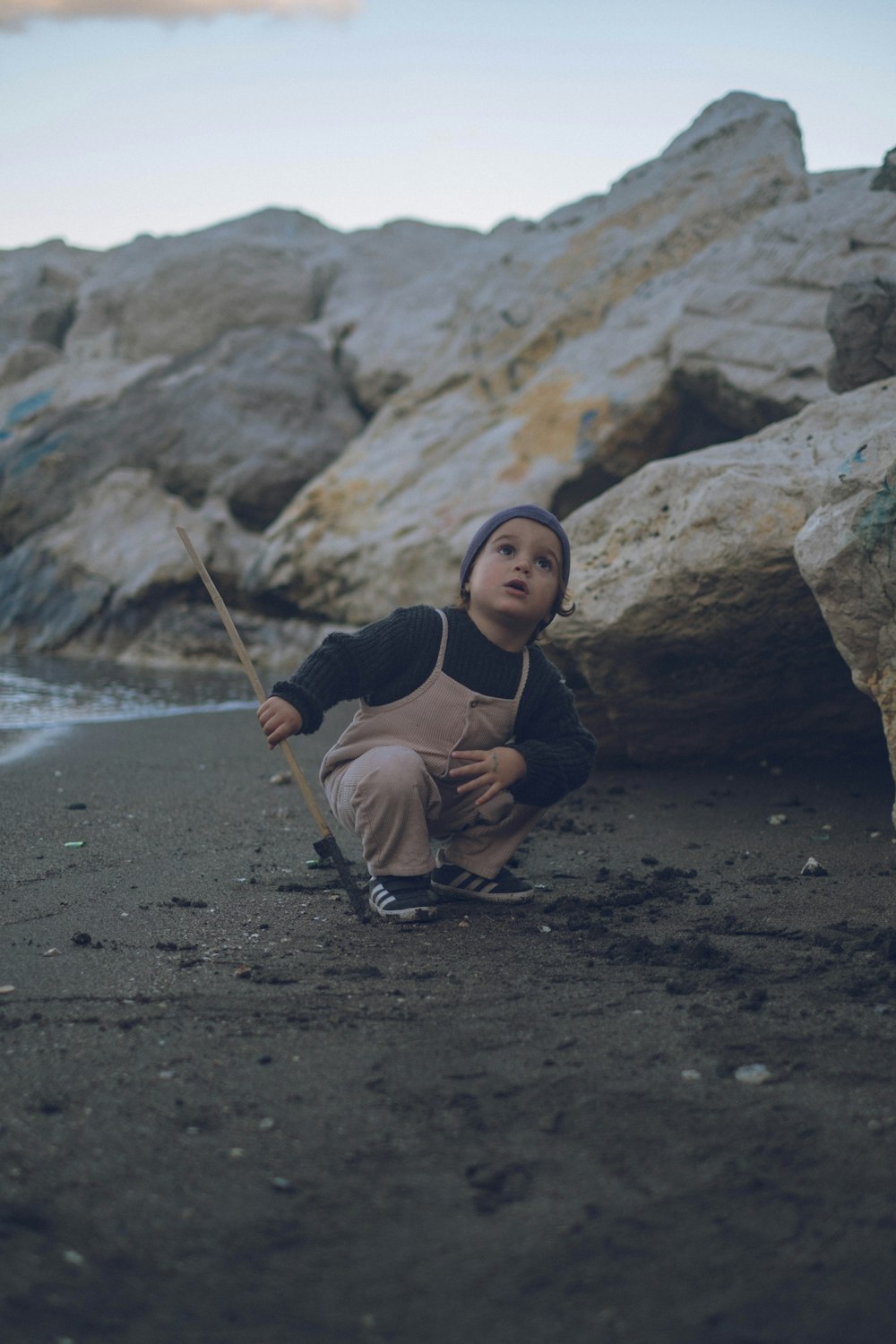 woman in black tank top sitting on brown sand during daytime