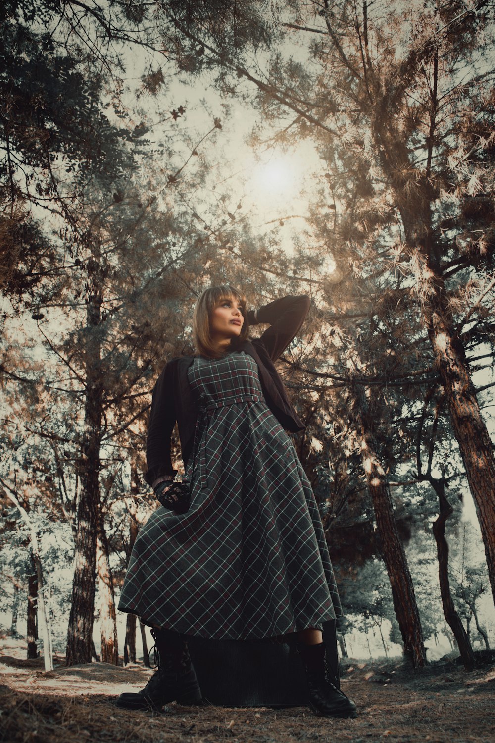 woman in black and white plaid dress shirt standing under brown tree during daytime