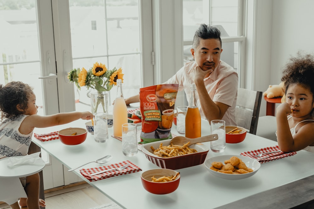 woman in white crew neck t-shirt sitting on chair in front of table with foods