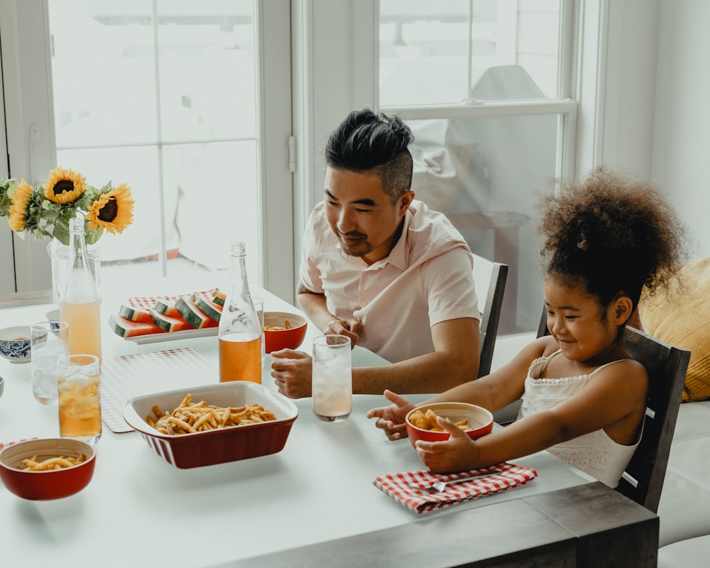 niño y niña comiendo en la mesa