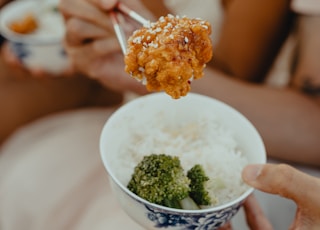 woman in white tank top holding spoon with rice