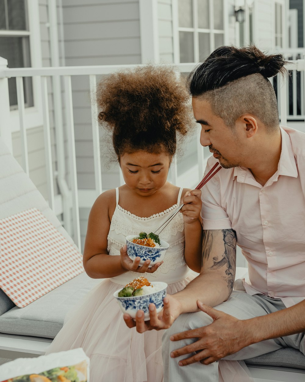 woman in white sleeveless dress holding girl in white tank top