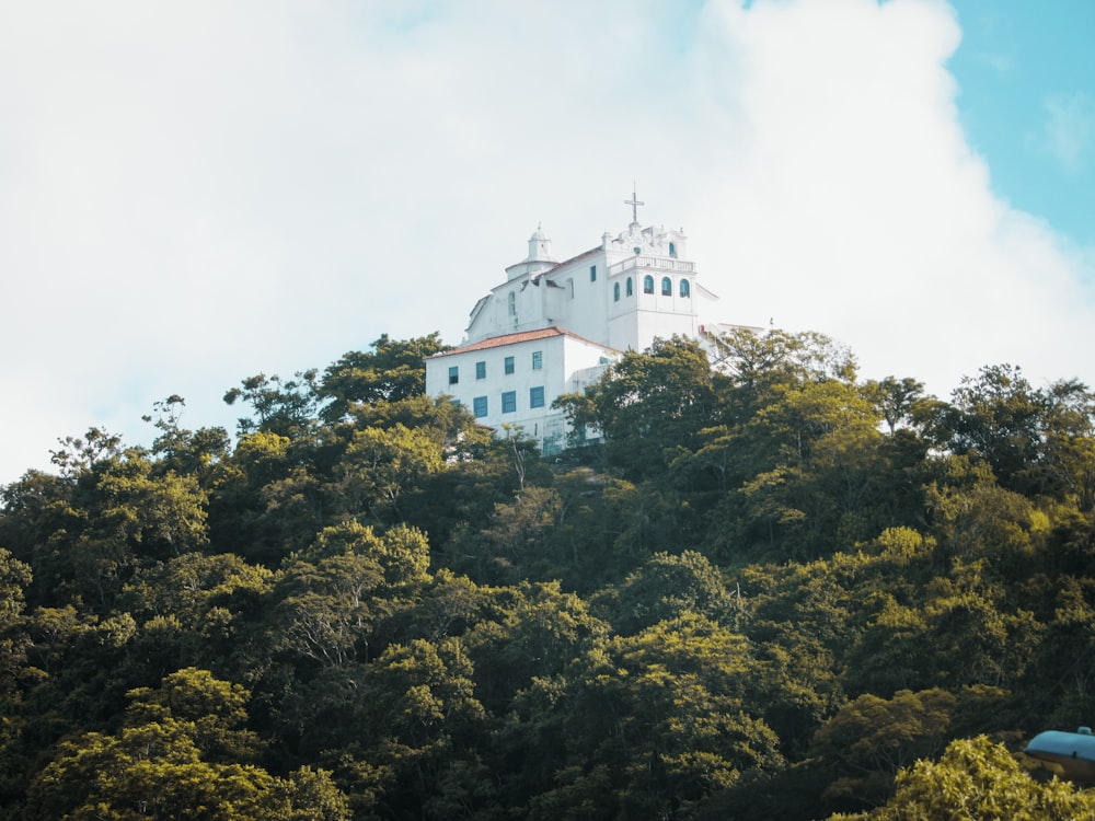 white concrete building surrounded by green trees under white sky during daytime