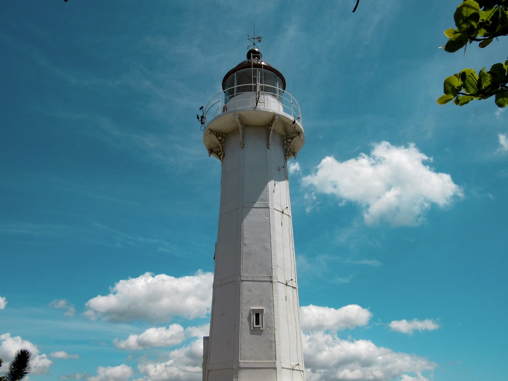 white and black lighthouse under blue sky and white clouds during daytime