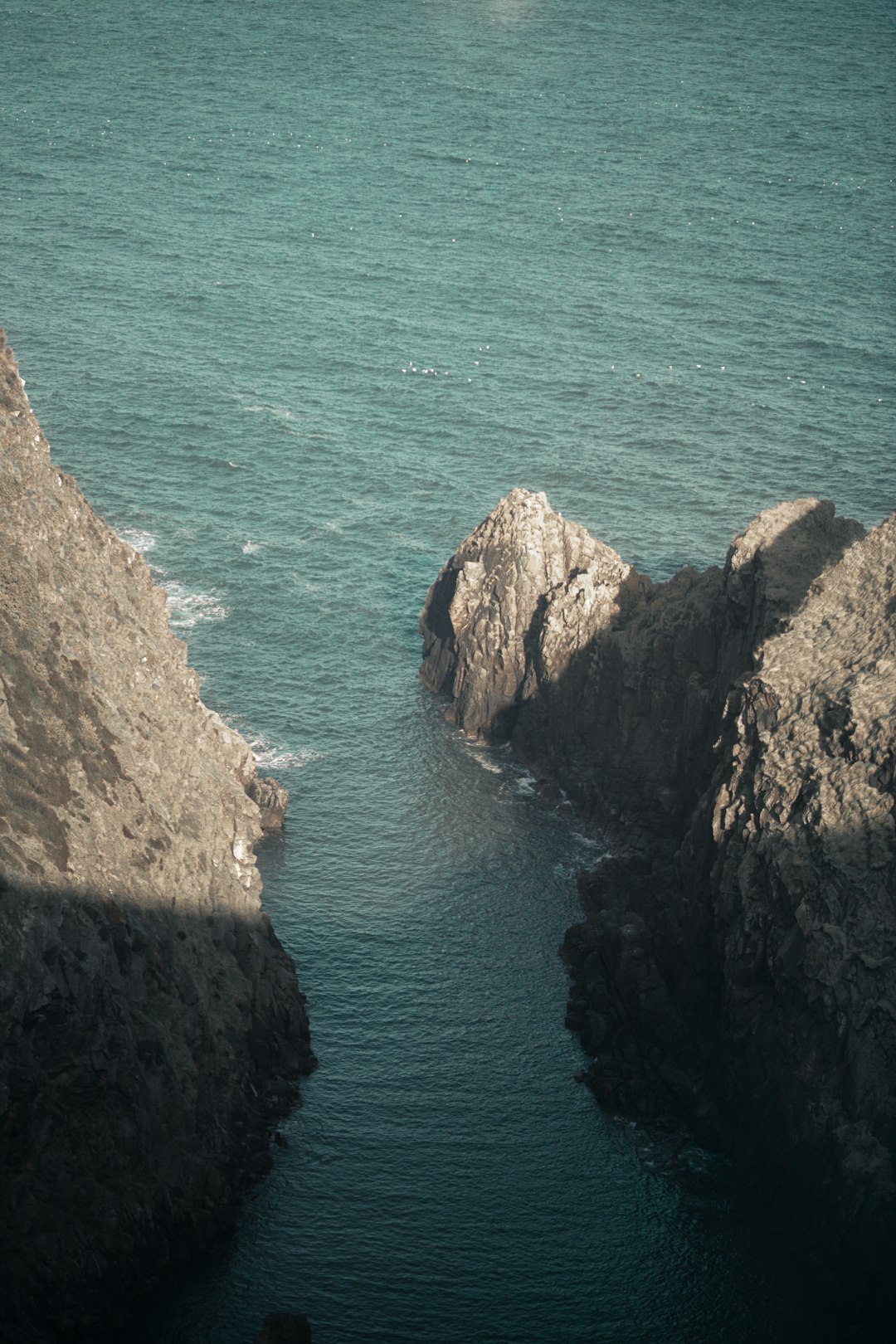 brown rocky mountain beside blue sea during daytime