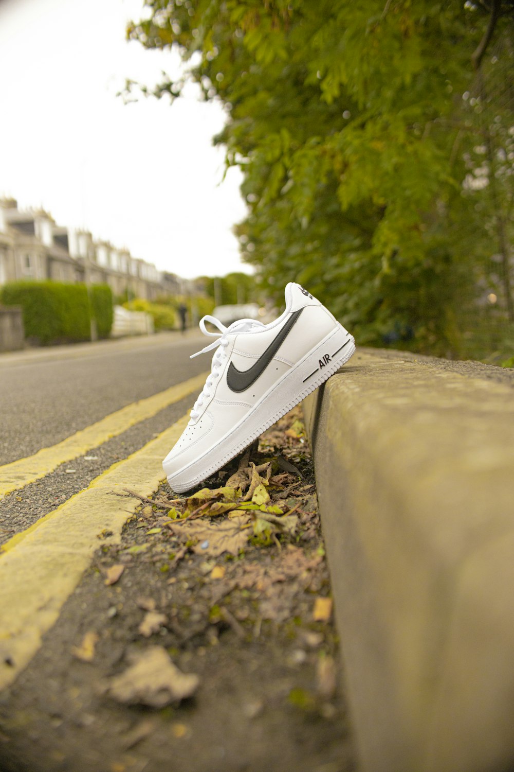Zapatillas Nike de caña baja blancas sobre carretera de cemento gris