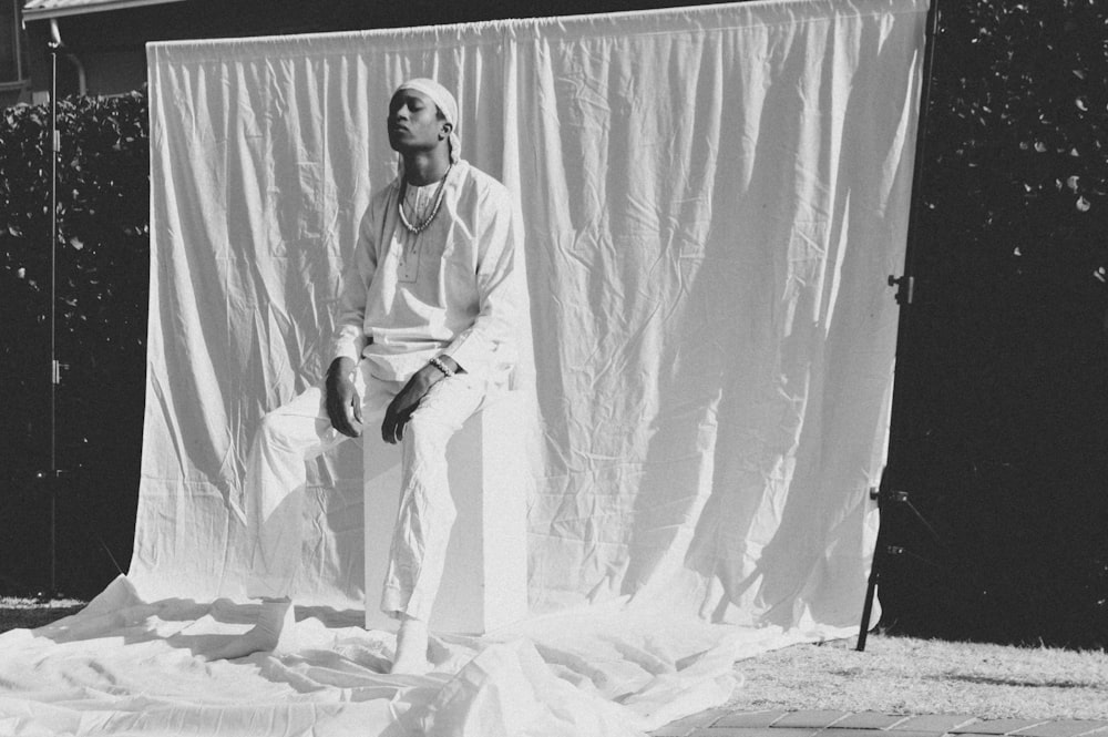 man in white dress shirt and black pants standing on white textile