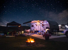 Families enjoying a campfire under a starry sky at the Ozark Outpost RV park.