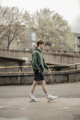 man in green jacket running on gray concrete road during daytime
