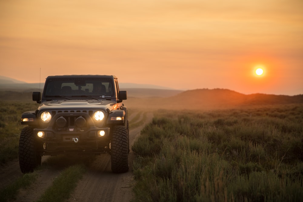 Jeep Wrangler noire sur un champ d’herbe verte au coucher du soleil