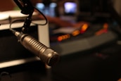 A close-up of a microphone set up for recording, with soft studio lighting highlighting its features.