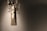 A professional microphone is suspended from a shock mount in a soundproof studio environment, with soft lighting highlighting its metallic and mesh texture against a plain backdrop.