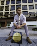 man in white dress shirt and blue denim jeans sitting on bench during daytime