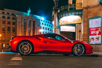A gleaming red exotic sports car parked on a city street at sunset, reflecting the vibrant urban lights.