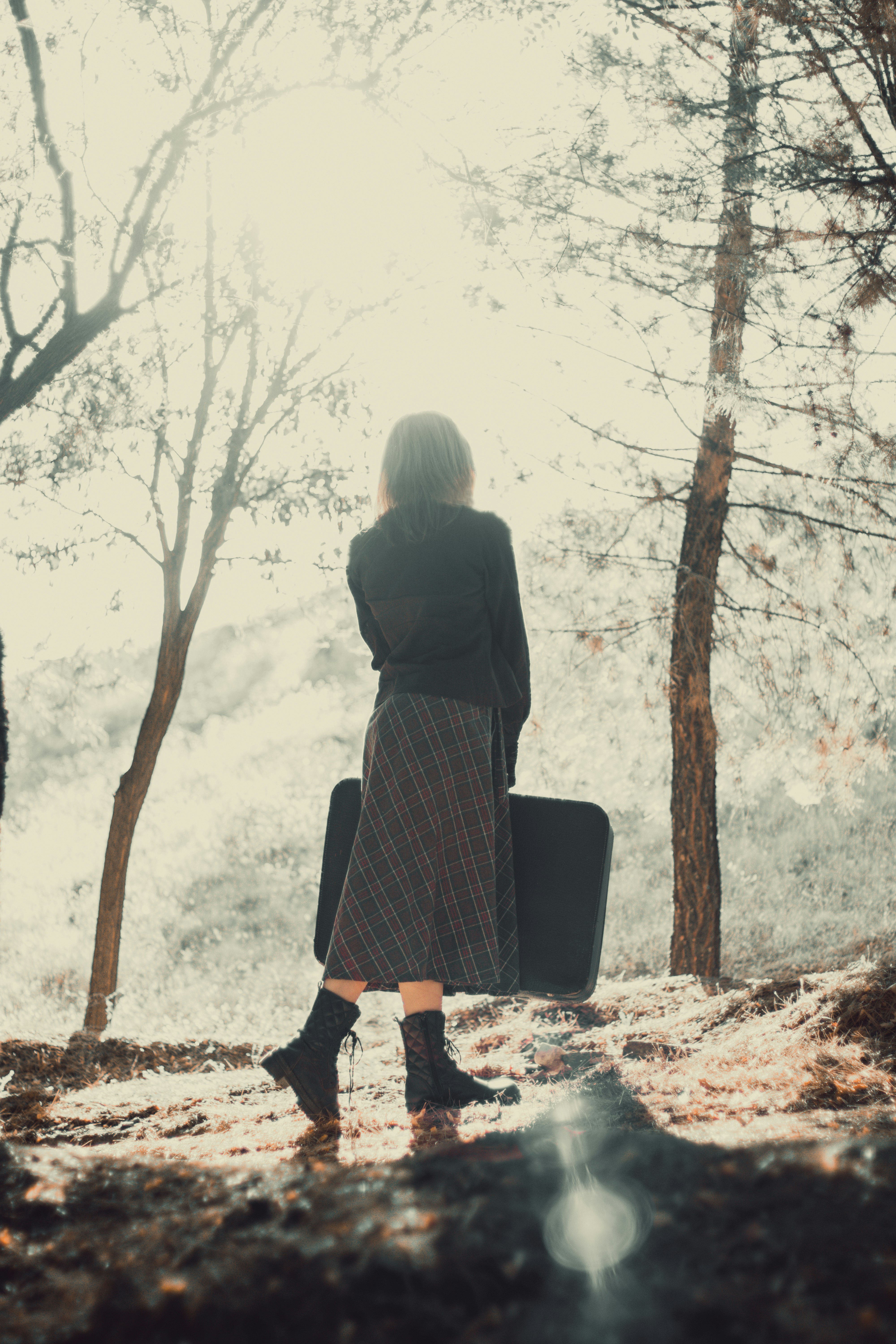 woman in black and white plaid dress standing near brown tree during daytime