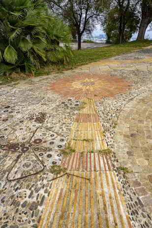 Patterned ceramic tiles creating a vibrant walkway through a sunny backyard.