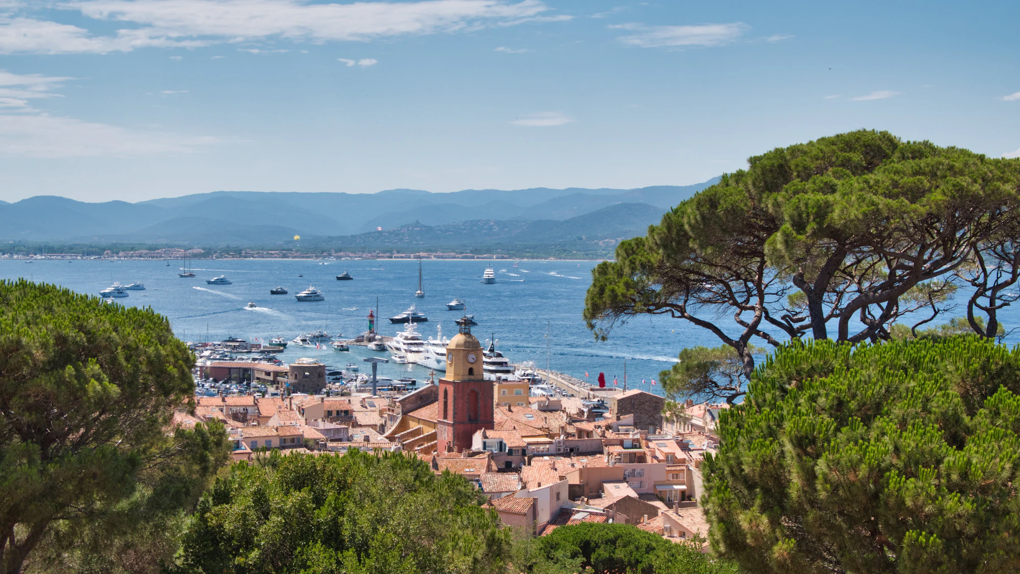 The Gulf of Saint-Tropez seen over the old town's rooftops and umbrella pines, the bay private jets bound for St Tropez La Mole fly over