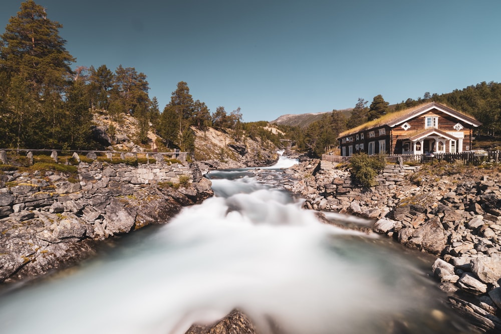 brown house near river under blue sky during daytime