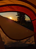 Sunrise casting golden light over tents pitched beside the riverbank.