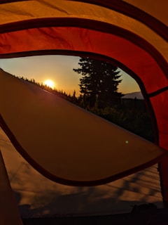 Sunrise over the Kedarnath valley with tents lined up, bathed in golden light and morning mist.