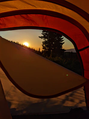 Sunrise casting golden light over tents pitched beside the riverbank.