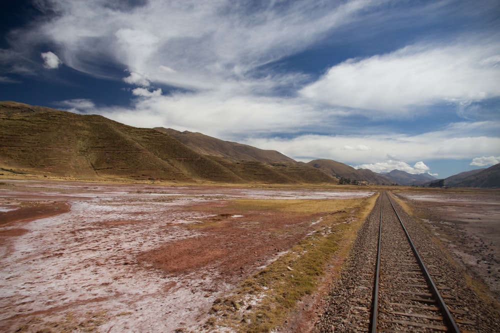 Campo de hierba marrón y verde cerca de la montaña bajo el cielo azul durante el día