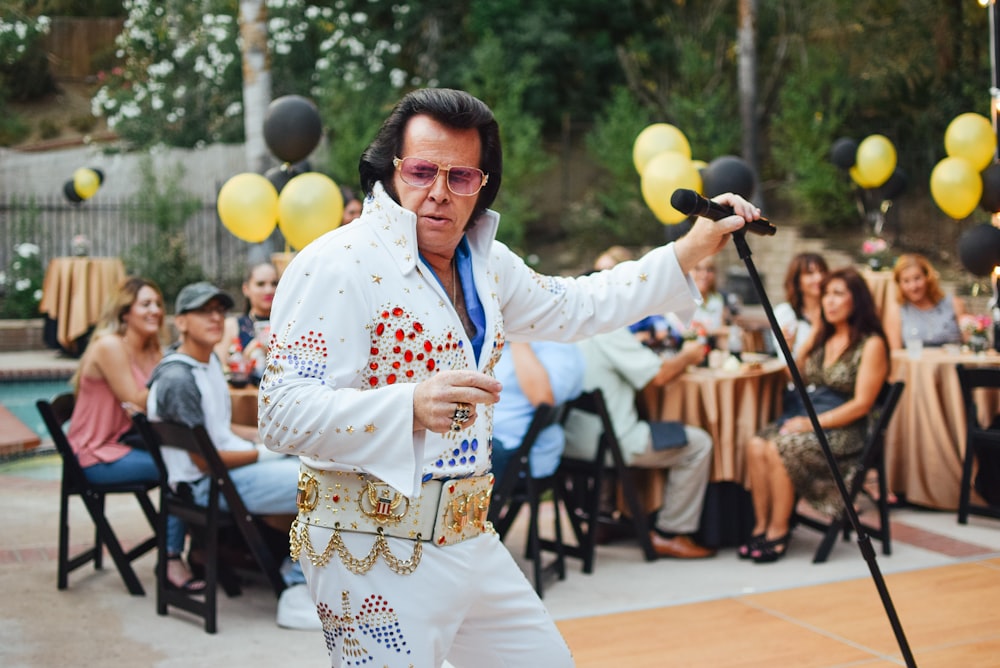 Un hombre vestido con ropa de Elvis sosteniendo un micrófono