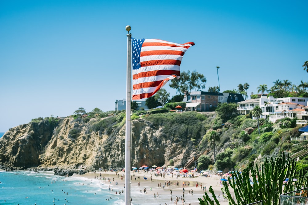 an american flag flying on a beach next to the ocean