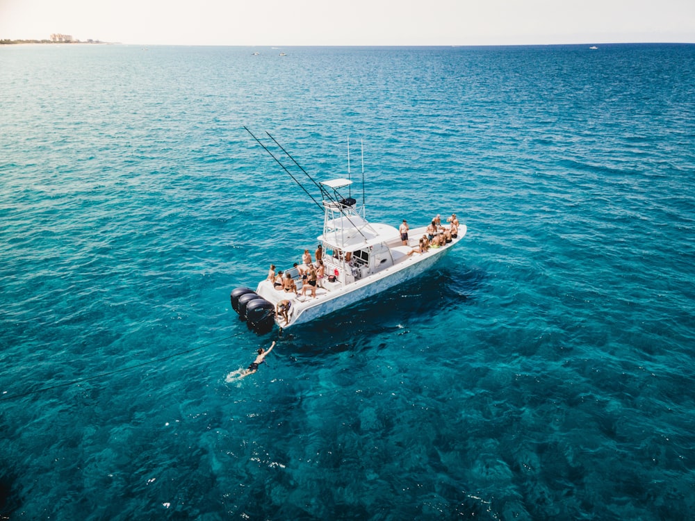 man in black wet suit riding on white and black boat on blue sea during daytime