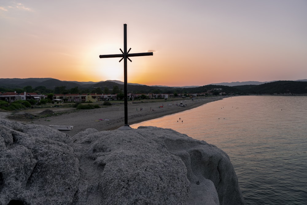 Braunes Holzkreuz tagsüber auf braunem Sand in der Nähe von Gewässern