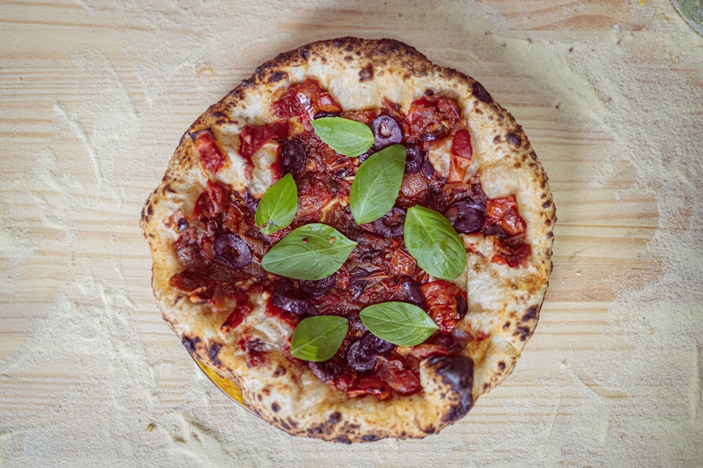 pizza with green leaves on brown wooden table